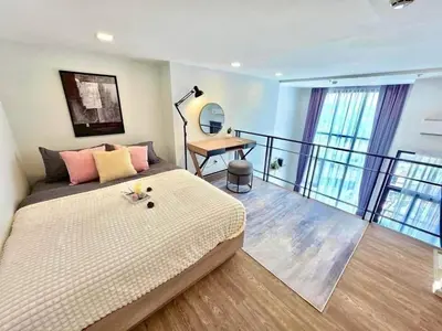 a bedroom with a bed and a balcony with a desk at Modiz Modiza Sukhumvit R3 in Bangkok