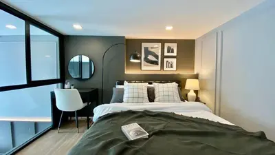 a bedroom with a bed and a desk and a window at Modiz Modiza Sukhumvit R4 in Bangkok