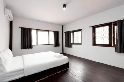 a bedroom with a bed with white sheets and windows at xx Mitr Inn Khaosan มิตร อินน์ ตรอกข้าวสาร in Bangkok