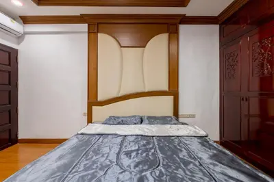 a bedroom with a bed with a wooden headboard at White Base in Bangkok