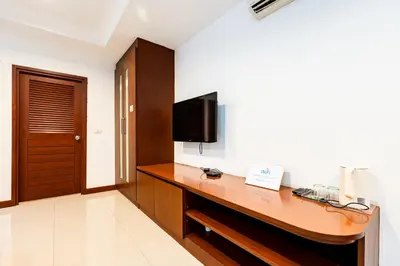 a hotel room with a desk with a tv on the wall at XX Yon INN Sukhumvit Soi 4 BTS Nana in Bangkok