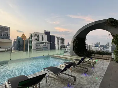 a pool on the roof of a building with chairs at Downtown Luxury Apartment, Asok Cowboy Lane, 400m from BTS in Bangkok