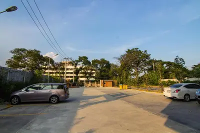 a parking lot with two cars parked in front of a building at Dae Ma Place in Nonthaburi