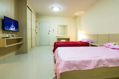 a hotel room with two beds and a tv at Dae Ma Place in Nonthaburi