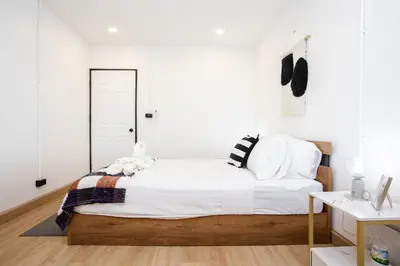 a bedroom with a large bed with white walls at Urban Muji Oasis Ratchada-Lat Phrao Chatuchak MRT in Bangkok