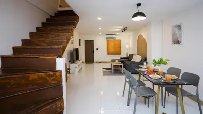 a living room with a table and chairs and a staircase at Urban Muji Oasis Ratchada-Lat Phrao Chatuchak MRT in Bangkok