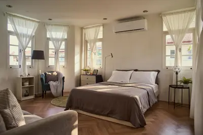 a bedroom with a bed and a chair and windows at Baan Suanpak in Bangkok