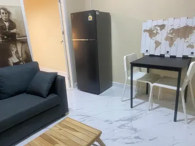 a living room with a couch and a table and a refrigerator at 1 Bed Nr IKEA 15Mins to Airport in Bangkok