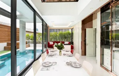 a dining room with glass walls and a pool at Modern Luxury Poolhaus with Lift in Khlong Toei