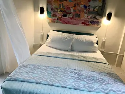 a bed with two pillows and a painting on the wall at Bali Style Rooftop Apartment in Bangkok