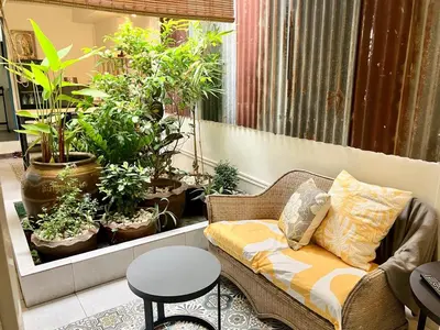 a couch sitting in a room with potted plants at Bali Style Rooftop Apartment in Bangkok