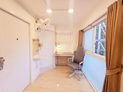 a room with a chair and a desk and a window at Crane nest 4 lower floor in Bangkok