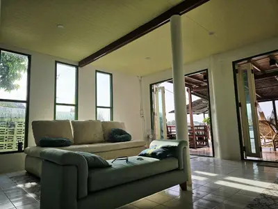 a living room with a couch and some windows at Sabai Sabai House Koh Kret in Ban Laem Yai