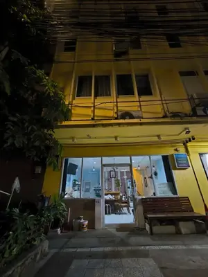 a yellow building with a bench in front of it at Santo house Bangkok in Bangkok