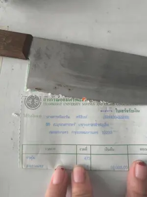 a person holding a piece of paper with a knife at Santo house Bangkok in Bangkok
