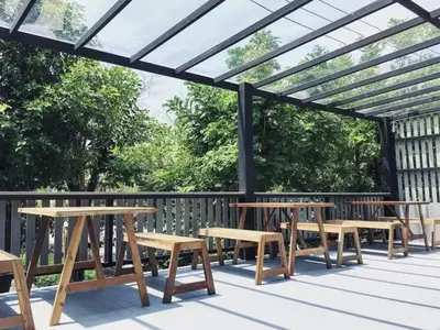 a wooden pergola with tables and benches on a deck at Sukhum Rajamangala-Phatthanakan Rooms in Bangkok