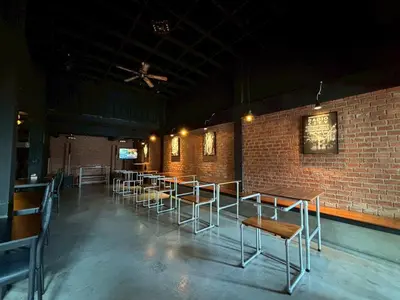 a row of tables and chairs in a room with a brick wall at Sukhum Rajamangala-Phatthanakan Rooms in Bangkok