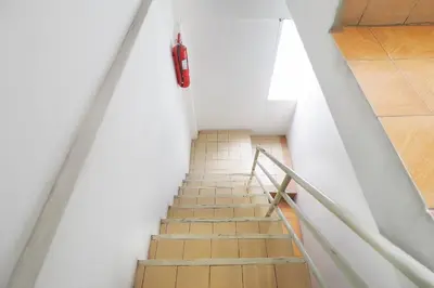 a staircase with a red fire extinguisher on the wall at Happyland Guesthouse in Bangkok