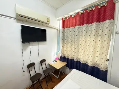 a room with two chairs and a table with a tv at Happyland Guesthouse in Bangkok