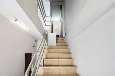 a staircase in a building with white walls and wooden floors at Happyland Guesthouse in Bangkok