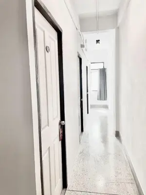 an empty hallway with white walls and a white door at XX Mitr inn Khaosan มิตร อินน์ ถนนข้าวสาร 2 in Bangkok