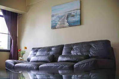 a black leather couch in a living room with a painting at Petch Tower Ekamai Budget Serviced Apartments in Bangkok