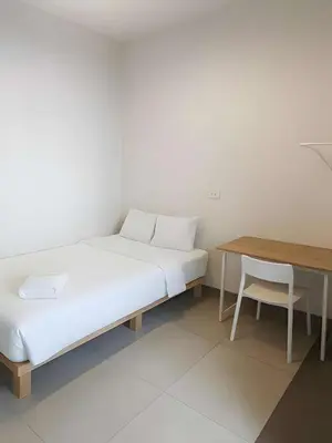 a bed in a room with a table and a chair at XX The Hidden khaosen เดอะ ฮิดเด้น ตรอกข้าวสาร in Bangkok