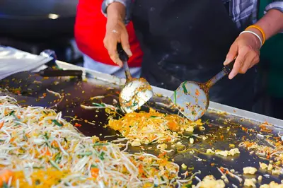 a person cooking food on a grill with spoons at XX The Hidden khaosen เดอะ ฮิดเด้น ตรอกข้าวสาร in Bangkok