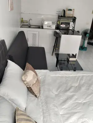 a bed with a pillow and a table in a room at แม่น้องรับตังค์ in Thung Si Kan