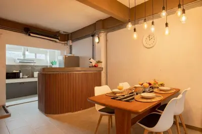 a dining room table with chairs and a clock on the wall at Urban Nest Townhouse, Local-feel, Roof,Nightmarket in Bangkok