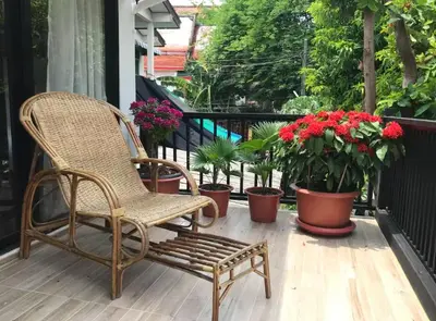 a wicker chair sitting on a porch with potted plants at Baan Ploen Dee - Wat Arun in Bangkok