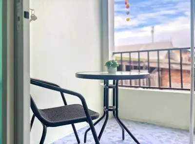 a table and a chair on a balcony at Baan Ploen Dee - Wat Arun in Bangkok