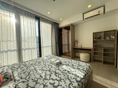 a bedroom with a bed and a desk and window at The Prestige Suites Rama 9 in Bangkok