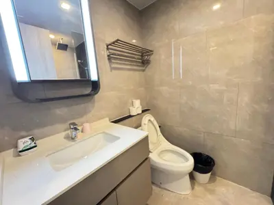 a bathroom with a sink and a toilet and a mirror at The Prestige Suites Rama 9 in Bangkok