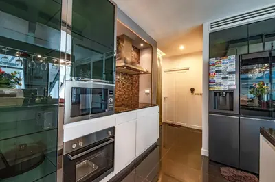 a kitchen with a stove and a microwave at Luxury Pure Modern Pool Villa 5Bed KTV Gym Nr BTS&Central in Bangkok