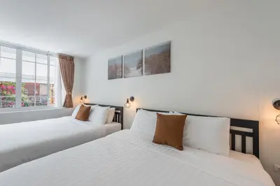 two beds in a bedroom with white walls and windows at The Urban478 Modern&Cozy Stay in Bangkok