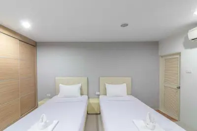 two beds in a room with white sheets at Townhouse Siam Privi Hotel in Bangkok