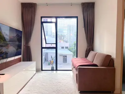 a living room with a couch and a large window at Best City Location with 3-min Walk to Everything in Bangkok