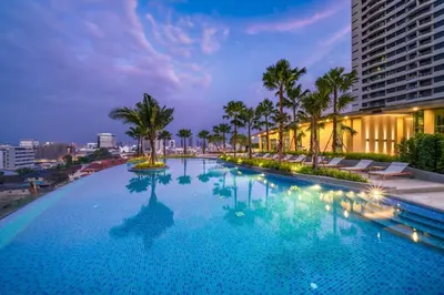 a large swimming pool with palm trees and a building at Amazing Pool and Luxury Condo Unit Near Phrom Phong BTS in Bangkok