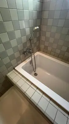 a bath tub with a shower in a tiled bathroom at Tree Villa Bangkok in Bangkok