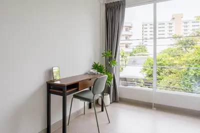 a desk and a chair in a room with a window at Glow House Sukhumvit 54 in Bangkok
