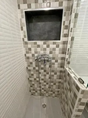 a bathroom with a shower with tiled walls at Vibrant City Retreat 6 Mins Walk BTS Nana, 1BR in Bangkok