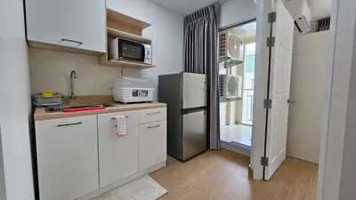 a small kitchen with white cabinets and a refrigerator at Easy Living in Bang Khen