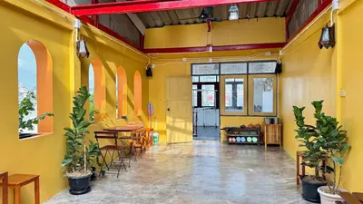 a room with yellow walls and tables and chairs at Baan PadSeeEw - Rooftop Riverview 2nd floor in Thonhuri