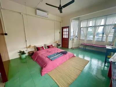 a bedroom with a large bed with a pink blanket at Baan KhaoSoi - Rooftop House in Talad Noi in Samphanthawong