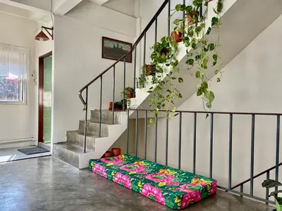 a couch sitting in a room next to a staircase at Baan KhaoSoi - Rooftop House in Talad Noi in Samphanthawong