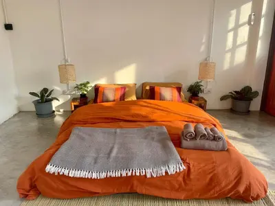an orange bed with two pairs of shoes on it at Baan KhaoSoi - Rooftop House in Talad Noi in Samphanthawong