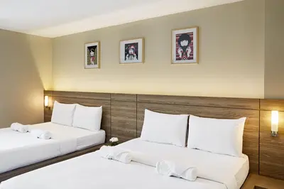 two beds in a hotel room with white pillows at Diamond Residence Ratchada in Bangkok