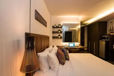 a bedroom with a bed with white pillows and a desk at Aim House Bangkok No Parking in Bangkok