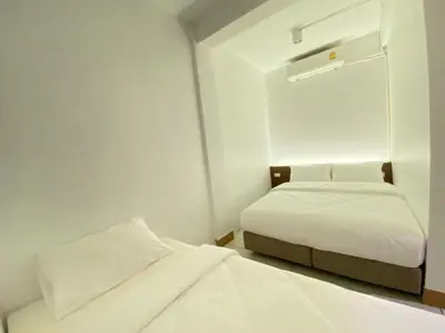 two beds in a small room with white walls at Kudi Hostel in Bangkok